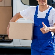 Two removal company workers unloading boxes from minibus into new home