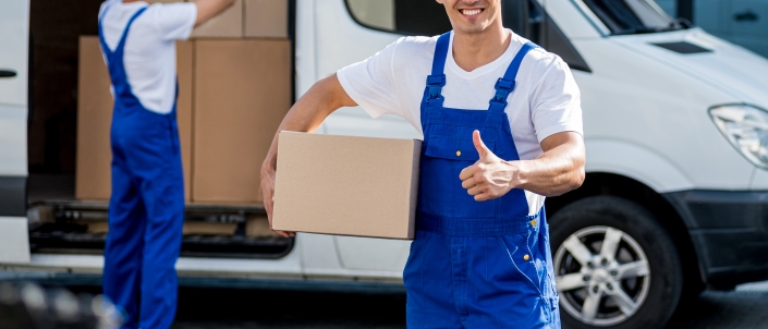 Two removal company workers unloading boxes from minibus into new home