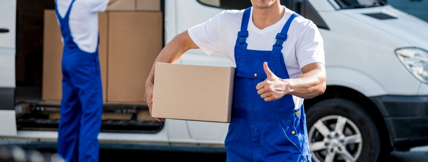Two removal company workers unloading boxes from minibus into new home