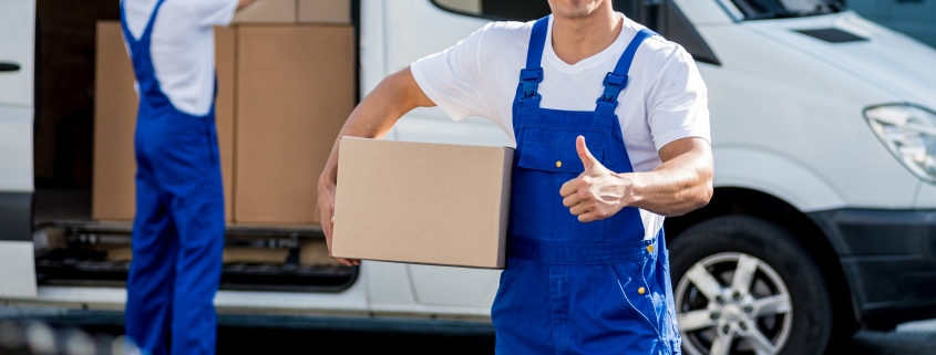 Two removal company workers unloading boxes from minibus into new home